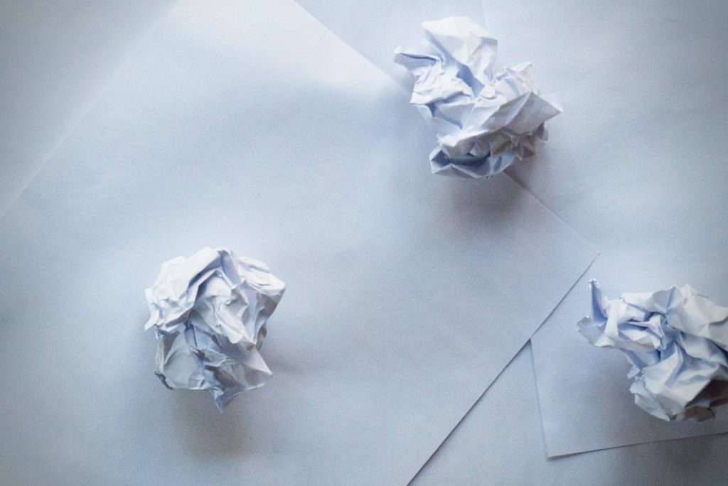 Crumpled pieces of white paper sitting on white paper background