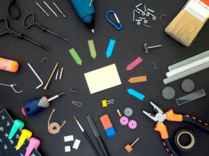 Colorful tools and office supplies laid out on a black background.